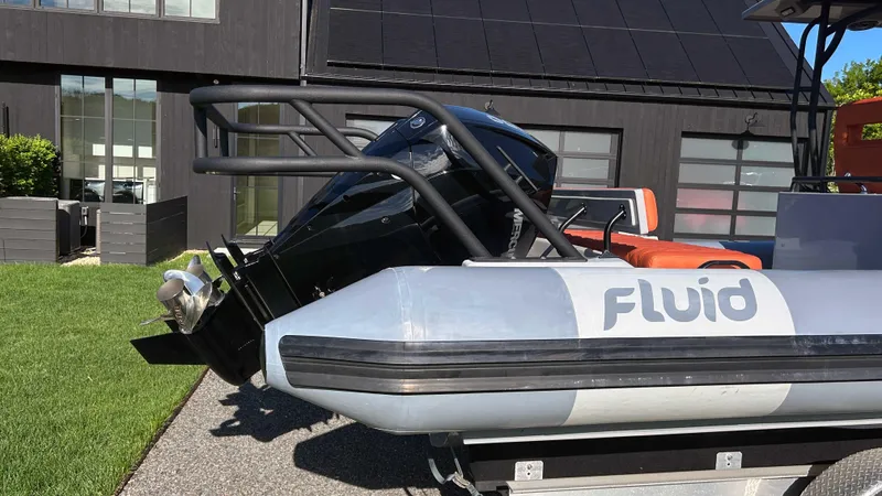  Yacht Photos Pics 2023 Fluid Watercraft M35 boat with outboard motor, parked on a trailer near a modern building.