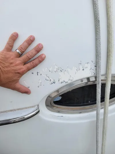All In Yacht Photos Pics Hand touching damaged paint on 2003 Lion Robertson & Caine Lion 46 boat exterior.