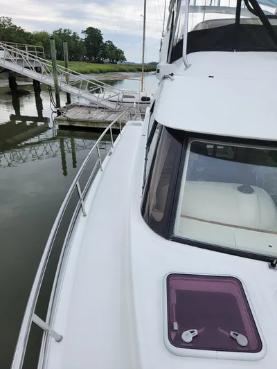 All In Yacht Photos Pics 2003 Robertson & Caine Lion 46 yacht docked by a serene waterfront.