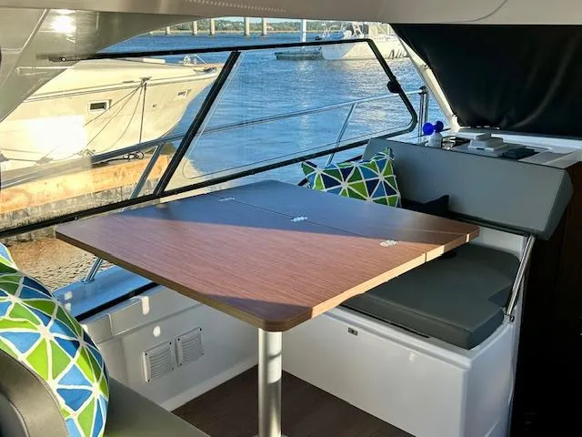 Sea Of Dreams Yacht Photos Pics Interior of 2024 Beneteau Antares 9 with dining table and colorful cushions.
