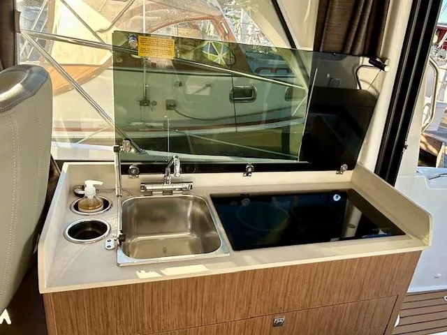 Sea Of Dreams Yacht Photos Pics 2024 Beneteau Antares 9 boat kitchen with sink, stove, and wooden cabinetry.