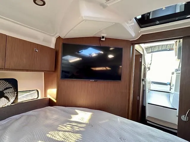 Sea Of Dreams Yacht Photos Pics 2024 Beneteau Antares 9 cabin interior with TV, wood paneling, and bed.