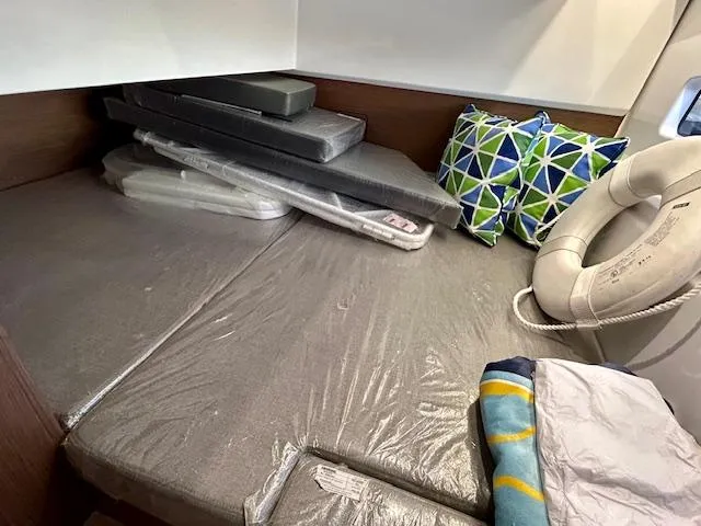 Sea Of Dreams Yacht Photos Pics 2024 Beneteau Antares 9 cabin with cushions, pillows, and a life preserver.