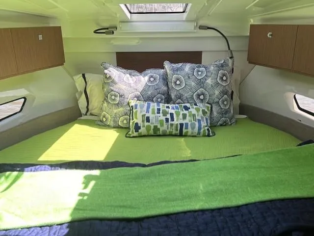 Sea Of Dreams Yacht Photos Pics 2024 Beneteau Antares 9 cabin interior with green bedding and decorative pillows.