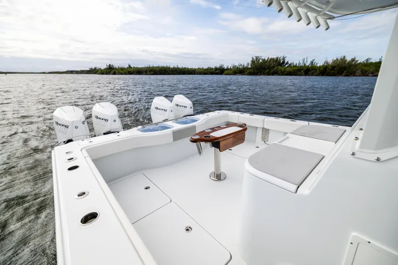  Yacht Photos Pics 2023 Freeman 43 boat deck with seating, table, and multiple outboard engines on a calm waterway.