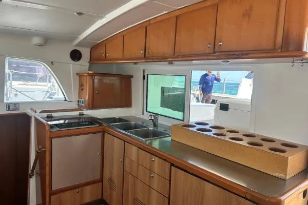 Dos Yacht Photos Pics Interior view of 2005 Lagoon 440 yacht kitchen with wooden cabinets and ocean view.