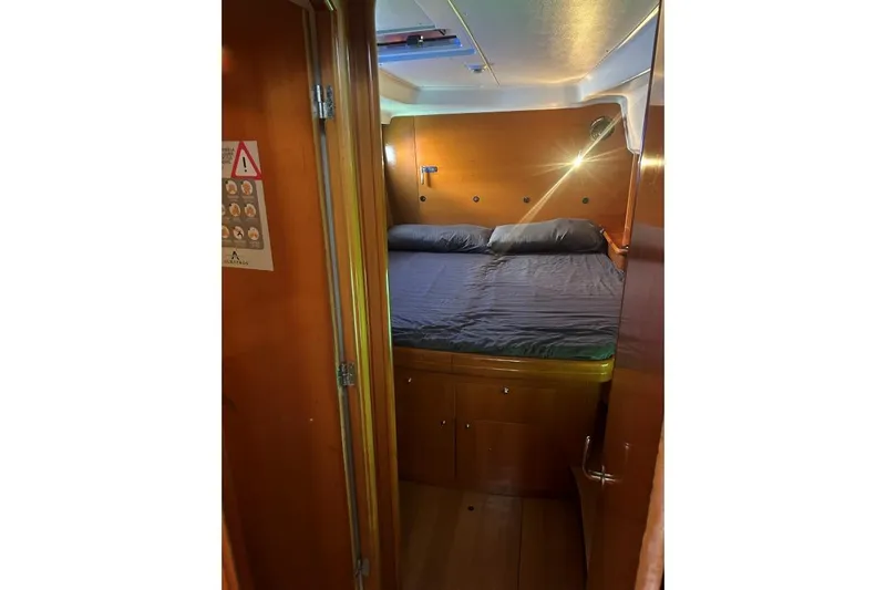 Dos Yacht Photos Pics Cozy cabin interior of 2005 Lagoon 440 catamaran with wooden finish and comfortable bedding.