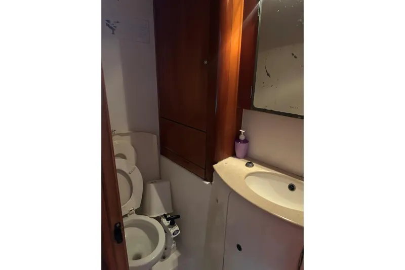 Dos Yacht Photos Pics Bathroom interior of 2005 Lagoon 440 yacht with sink, toilet, and wooden cabinetry.