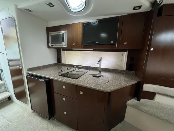  Yacht Photos Pics 2012 Cruisers Yachts 350 Express interior kitchen with microwave, TV, and compact fridge.