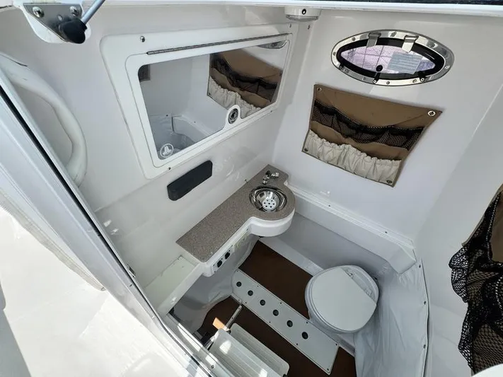  Yacht Photos Pics 2015 Southport 29 FE boat interior with compact bathroom, featuring a sink, toilet, and mirror.