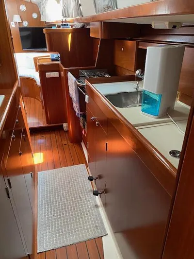 Rogue Fun Yacht Photos Pics 2001 Beneteau Oceanis 44 CC yacht interior with wooden cabinetry and compact kitchen area.