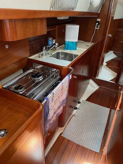 Rogue Fun Yacht Photos Pics 2001 Beneteau Oceanis 44 CC yacht kitchen with stove, sink, and wooden cabinetry.