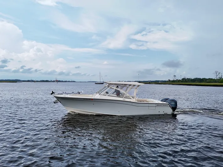  Yacht Photos Pics 2022 Grady-White Freedom 307 boat cruising on a calm river under a cloudy sky.