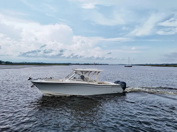  Yacht Photos Pics 2022 Grady-White Freedom 307 boat cruising on a calm river under a cloudy sky.