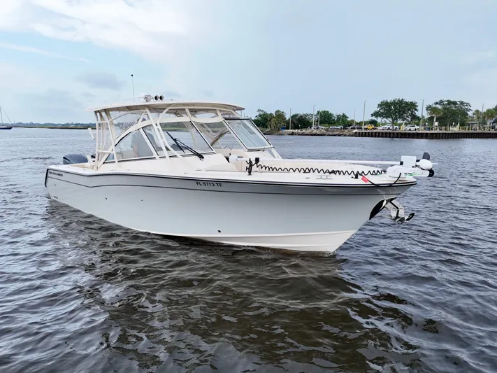  Yacht Photos Pics 2022 Grady-White Freedom 307 boat cruising on a calm river under a cloudy sky.