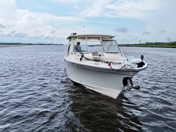  Yacht Photos Pics 2022 Grady-White Freedom 307 boat on calm water under a cloudy sky.