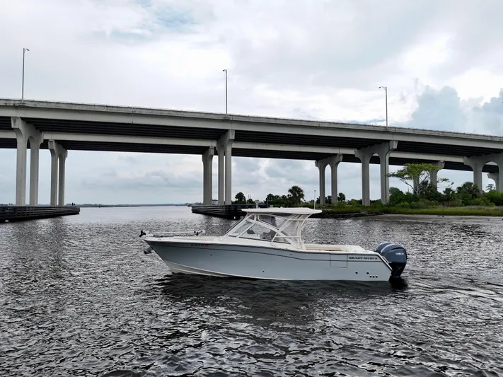  Yacht Photos Pics 2022 Grady-White Freedom 307 boat cruising under a large bridge on a cloudy day.