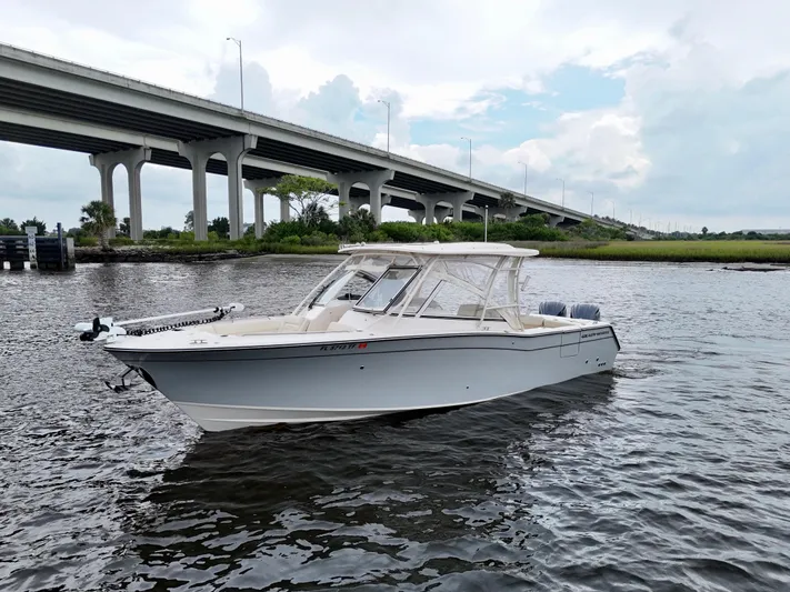  Yacht Photos Pics 2022 Grady-White Freedom 307 boat on water near a bridge, under a cloudy sky.