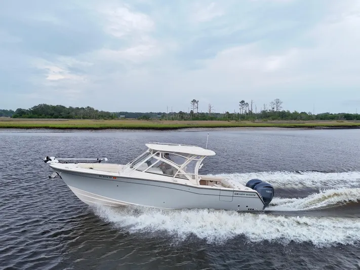  Yacht Photos Pics 2022 Grady-White Freedom 307 boat cruising on a calm river under a cloudy sky.