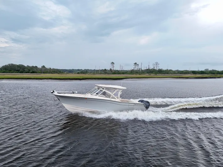  Yacht Photos Pics 2022 Grady-White Freedom 307 cruising on a calm river under a cloudy sky.