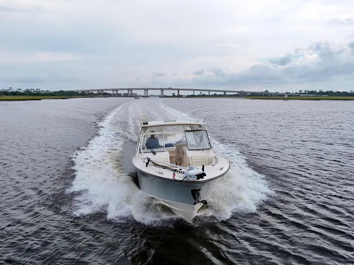 Yacht Photos Pics 2022 Grady-White Freedom 307 boat cruising on a river with a bridge in the background.