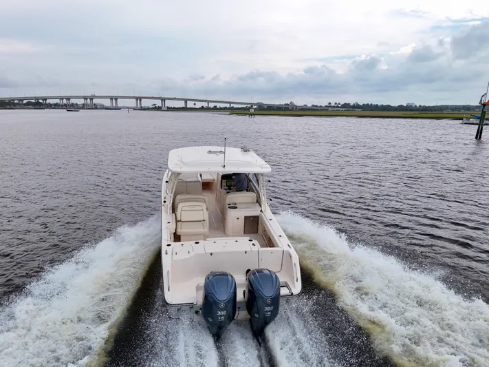  Yacht Photos Pics 2022 Grady-White Freedom 307 boat cruising on a river with a bridge in the background.