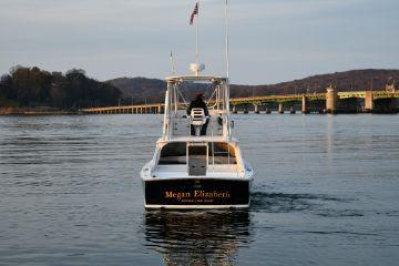 1965 Bertram Sportfisher boat on calm water near a bridge.