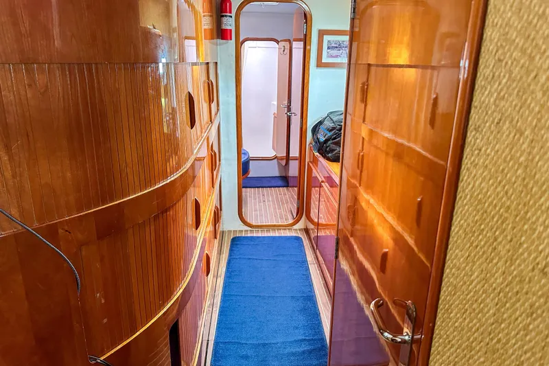 Mystic Yacht Photos Pics Luxurious wooden interior of 2001 Privilege 435 yacht with blue carpeted hallway.