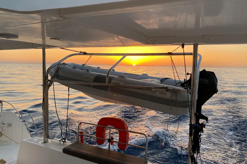  Yacht Photos Pics Lagoon 42 catamaran at sunset, featuring a dinghy and calm ocean waters.