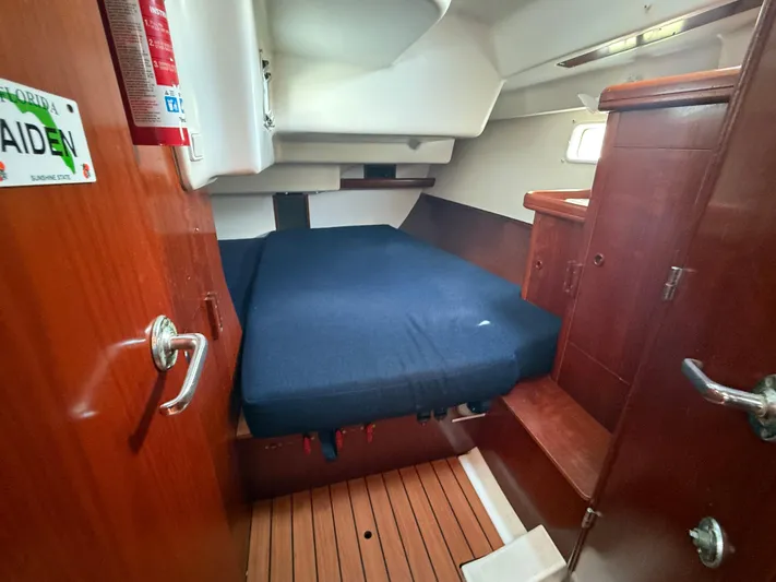 Traveler Yacht Photos Pics Cozy cabin interior of 2002 Beneteau 473 sailboat with wooden finish and blue bedding.