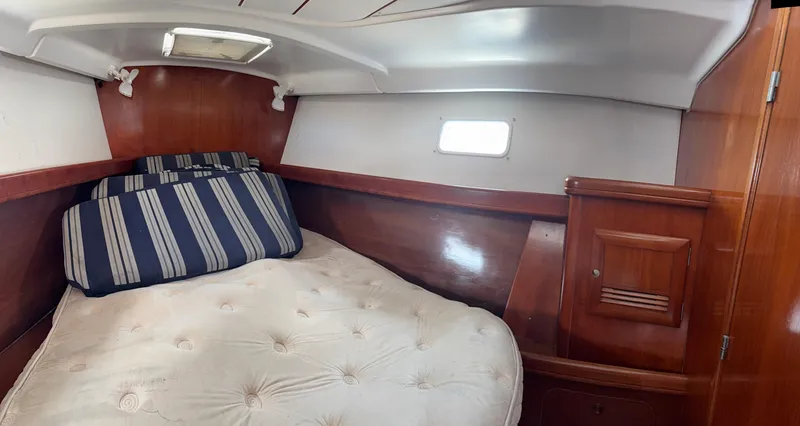 Traveler Yacht Photos Pics Cozy cabin interior of 2002 Beneteau 473 sailboat with wooden finish and striped cushions.
