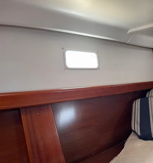 Traveler Yacht Photos Pics Interior cabin of 2002 Beneteau 473 sailboat with wooden paneling and small window.
