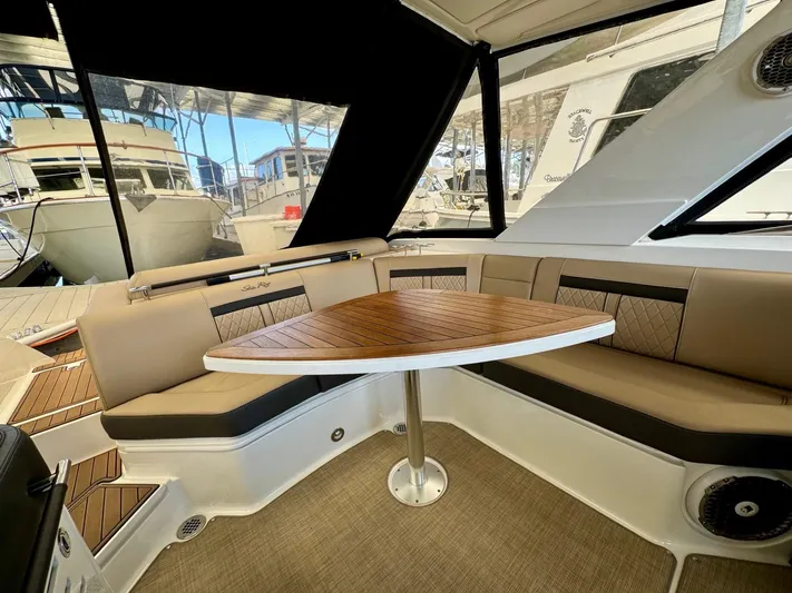  Yacht Photos Pics Interior seating area of 2018 Sea Ray SLX 310 boat with wooden table.