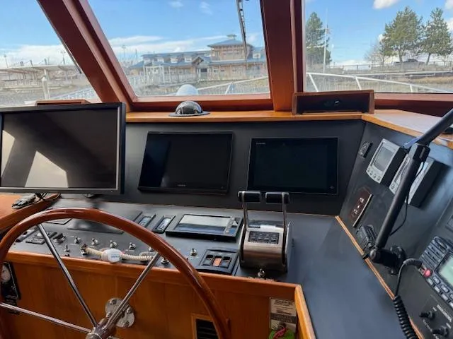 Fellowship Yacht Photos Pics Pilothouse interior of 2001 Grand Alaskan yacht with navigation equipment and steering wheel.