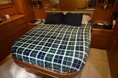 Fellowship Yacht Photos Pics Luxurious 2001 Grand Alaskan Pilothouse bedroom with plaid bedding and wooden cabinetry.