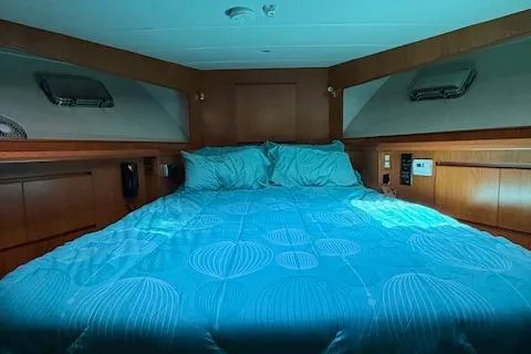 Fellowship Yacht Photos Pics 2001 Grand Alaskan Pilothouse cabin with blue bedding and wooden interior.