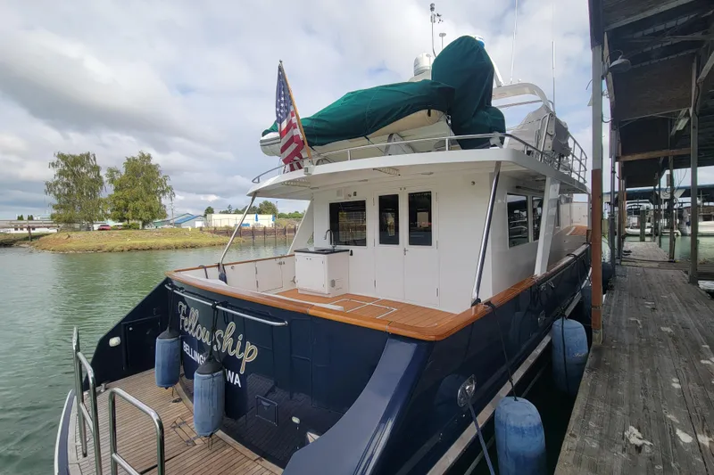 Fellowship Yacht Photos Pics 2001 Grand Alaskan Pilothouse yacht docked, featuring a spacious deck and American flag.