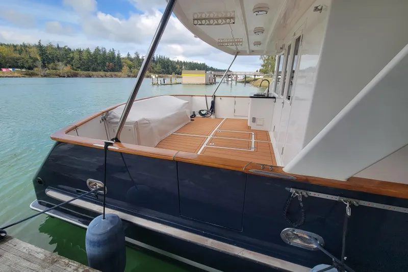 Fellowship Yacht Photos Pics 2001 Grand Alaskan Pilothouse yacht with spacious deck, docked by serene waters.