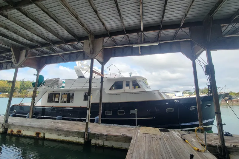 Fellowship Yacht Photos Pics 2001 Grand Alaskan Pilothouse yacht docked under a covered marina.