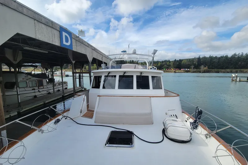 Fellowship Yacht Photos Pics 2001 Grand Alaskan Pilothouse yacht docked at marina under cloudy sky.