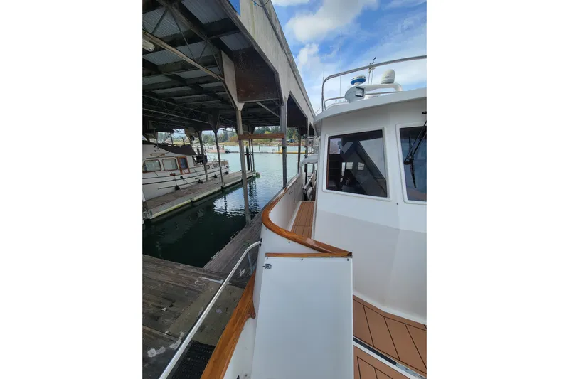 Fellowship Yacht Photos Pics 2001 Grand Alaskan Pilothouse yacht docked under a covered marina.