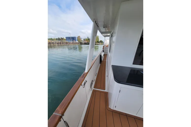 Fellowship Yacht Photos Pics Side deck view of 2001 Grand Alaskan Pilothouse yacht, featuring teak flooring and white exterior.