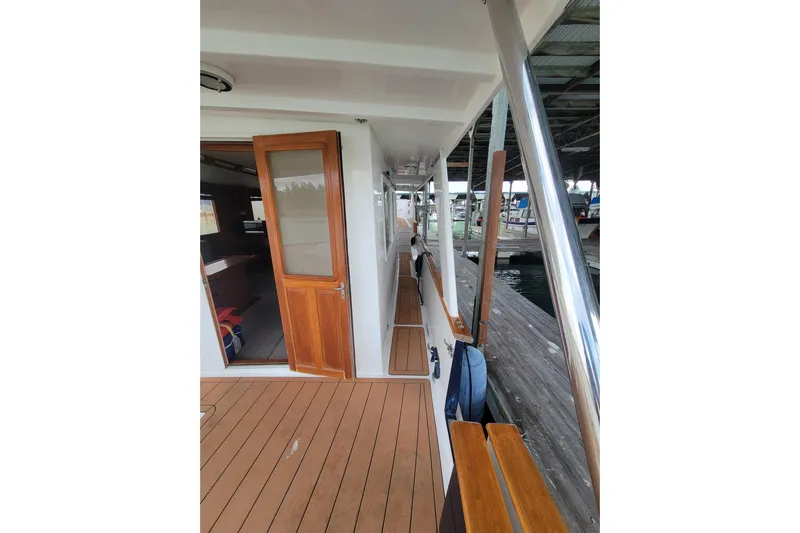 Fellowship Yacht Photos Pics 2001 Grand Alaskan Pilothouse yacht with wooden deck and open cabin door.