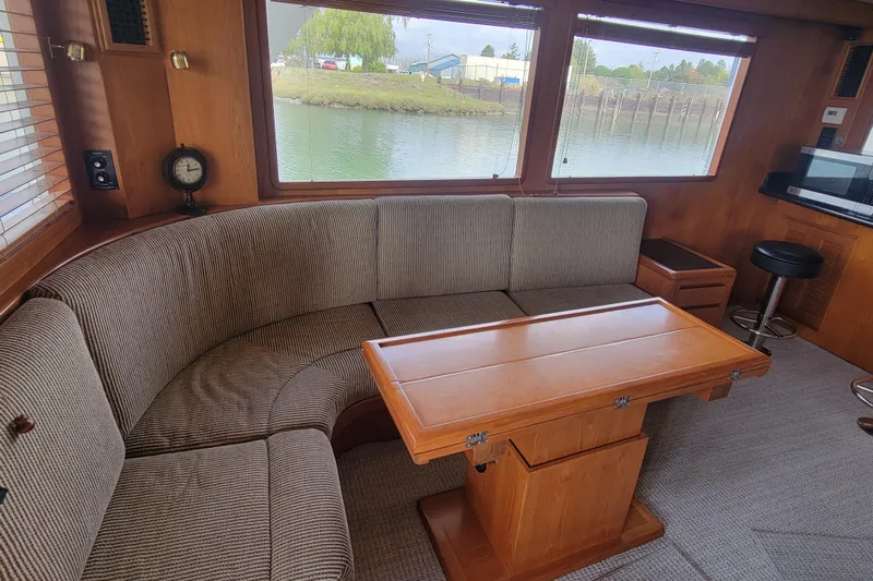 Fellowship Yacht Photos Pics Interior of 2001 Grand Alaskan Pilothouse with cozy seating and wooden table.