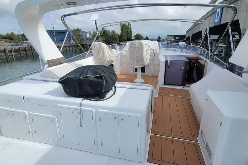 Fellowship Yacht Photos Pics 2001 Grand Alaskan Pilothouse yacht deck with seating and storage, docked by the waterfront.