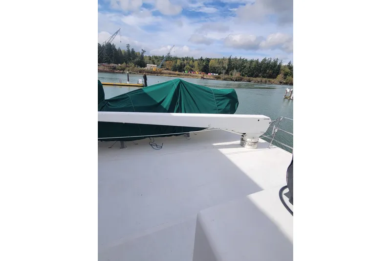 Fellowship Yacht Photos Pics 2001 Grand Alaskan Pilothouse deck with green cover, scenic waterfront view.