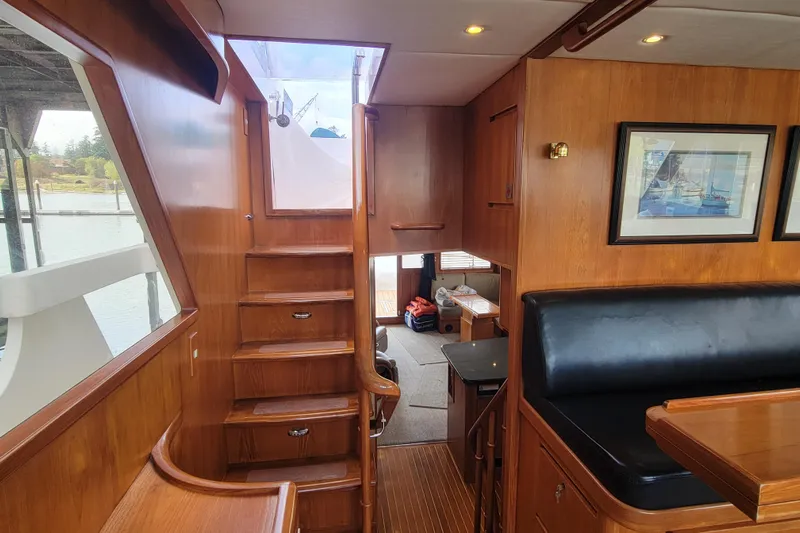 Fellowship Yacht Photos Pics Interior of 2001 Grand Alaskan Pilothouse yacht with wooden stairs and seating area.