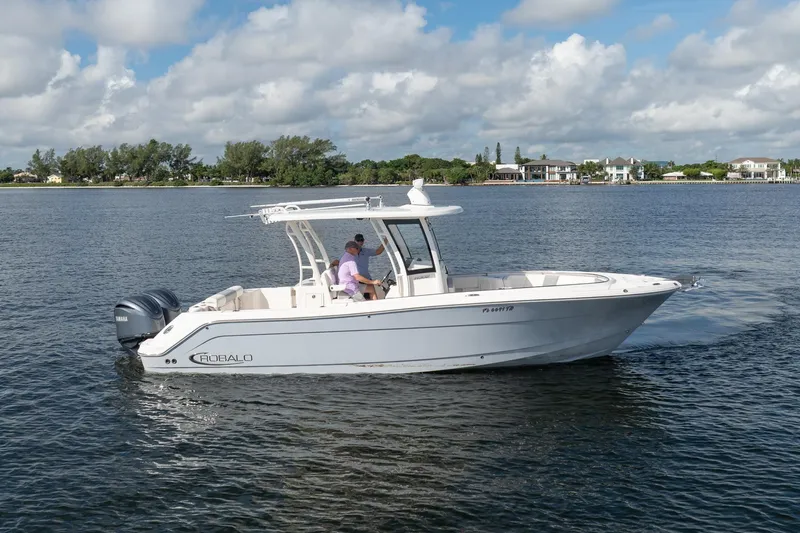 Hi Ho Silver Yacht Photos Pics 2022 Robalo R302 Center Console boat cruising on a calm lake under a cloudy sky.
