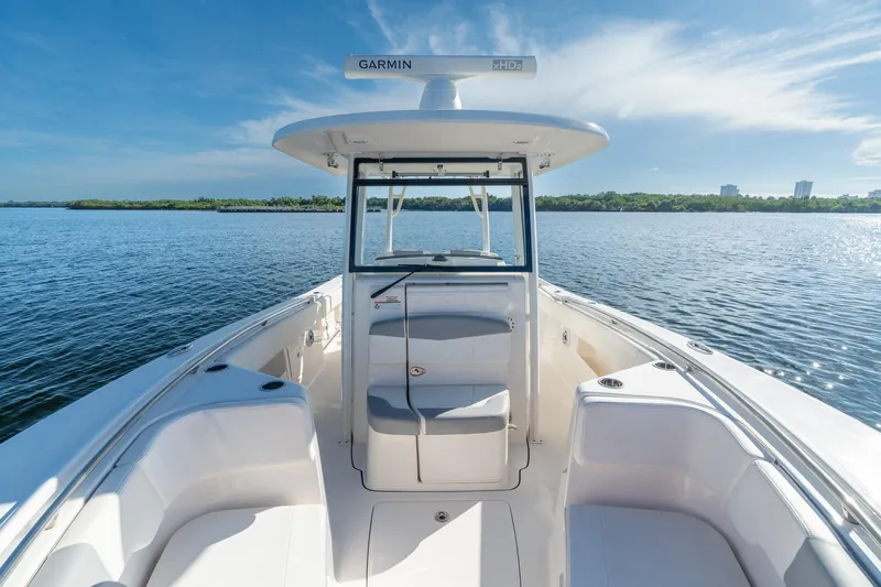 Hi Ho Silver Yacht Photos Pics 2022 Robalo R302 Center Console boat on calm water, clear sky, and lush shoreline.