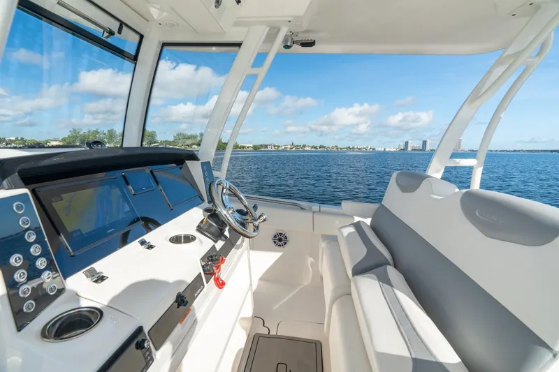 Hi Ho Silver Yacht Photos Pics 2022 Robalo R302 Center Console boat interior with steering wheel and seating, overlooking calm waters.